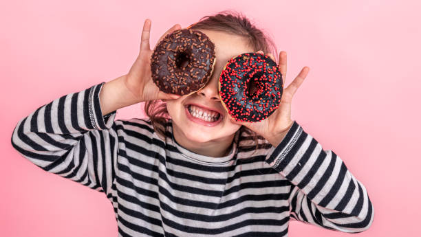 istock Funny little girl with donuts on a pink background. 1346012303
