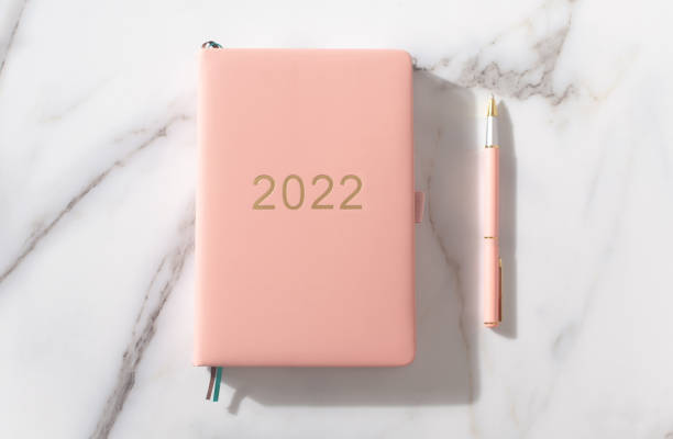 istock Pink coral colored diary for the year 2022, pen. Marble background 1346014124