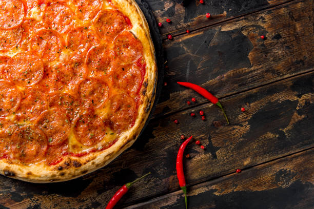 istock Pepperoni pizza with spicy pepper on dark wooden table top view with copy space for text. 1346015044