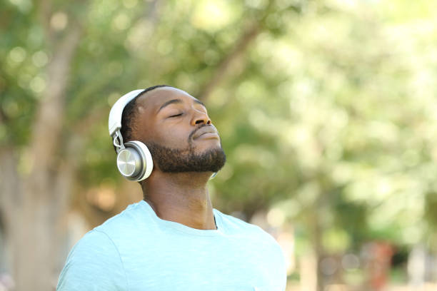 feliz hombre negro escuchando audioguía y respirando - mobile phone telephone bluetooth men fotografías e imágenes de stock