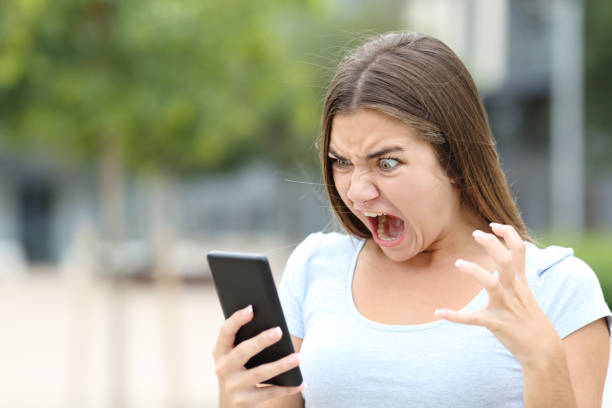 wütender teenager, der medien auf dem smartphone sieht - mobile phone telephone frustration women stock-fotos und bilder