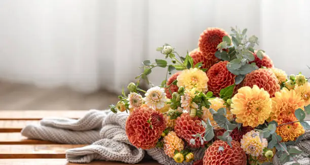 A bouquet of yellow and orange chrysanthemums and a knitted element on a blurred background, copy space.
