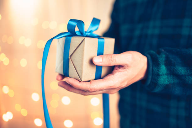 istock Hands holding gift box, present on the table and light of bokeh background. Valentine's Day, Christmas, Birth day, New year and Anniversary concept. 1346017576