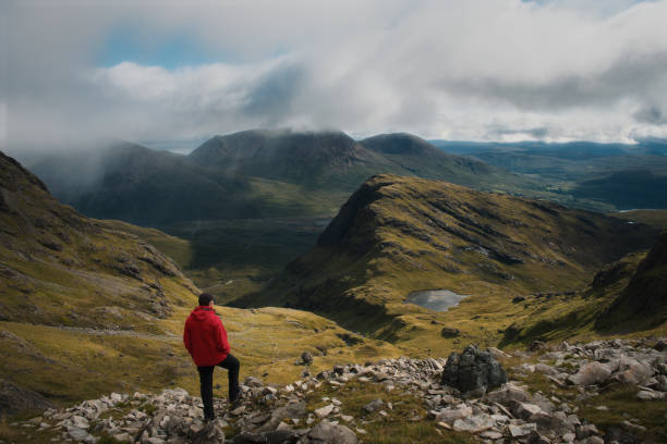 A hiker at the top of the mountain views the magnificent landscape of the Isle of Skye stock photo