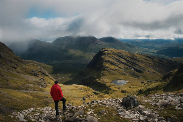 турист на вершине горы смотрит на великолепный пейзаж острова скай - scottish travel стоковые фото и изображения