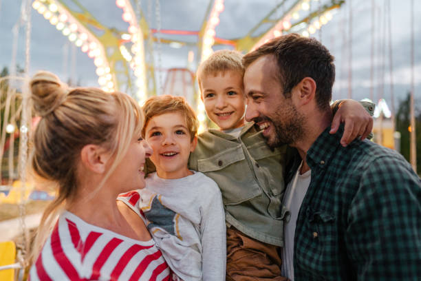 glückliche familie im vergnügungspark - freizeitpark stock-fotos und bilder