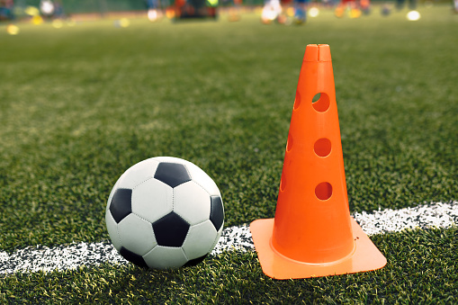 Soccer Ball and Training Cone Lying on Football Pitch Sideline. Soccer Training Equipment on School Practice Pitch