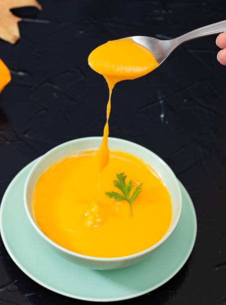 istock Metal spoon scooping delicious pumpkin puree from a plate. Selective focus. ready to eat 1346021121