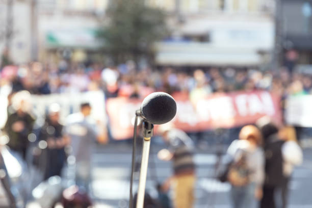 istock Protest or public demonstration, focus on microphone, blurred crowd of people in the background 1346023748