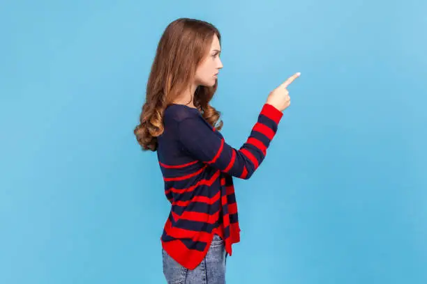 Photo of You better do what I say! Side view of strict bossy woman wearing striped casual sweater looking ahead with serious face and finger warning gesture.