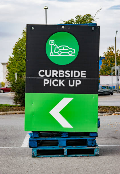 "CURBSIDE PICK UP" signage A " Curbside Pick Up" sign installed on the side of a stacked skids (wooden palette) in the parking lot of a  retailer store, Ontario, Canada - stock photography curbsidepickup stock pictures, royalty-free photos & images
