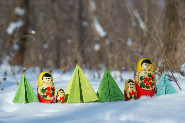 istock A row of nesting dolls and toy Christmas trees in a snowy forest. 1346026507