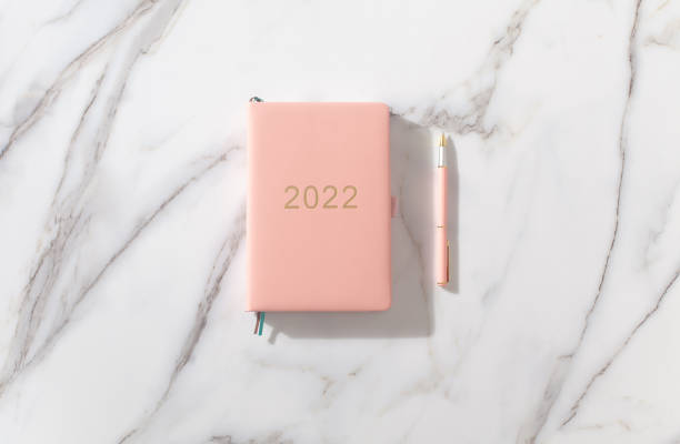 istock Pink coral colored diary for the year 2022, pen. Marble background 1346027179