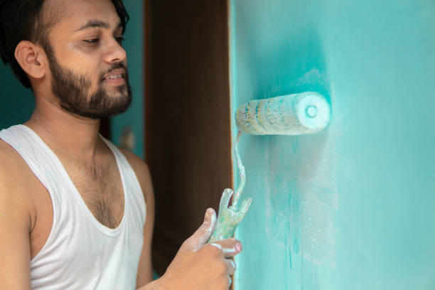 istock Indian man painting house wall with a paint roller. 1346027932