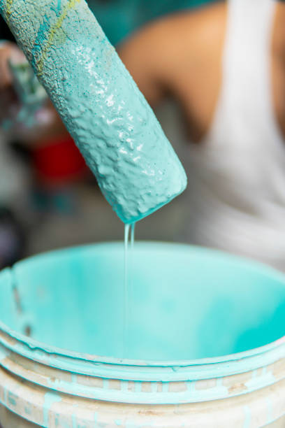 istock Painter mixing wall paint with paint roller in bucket. 1346028071