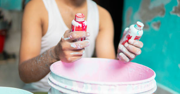 istock Painter holding color bottle, preparing paint for home decoration. 1346028104
