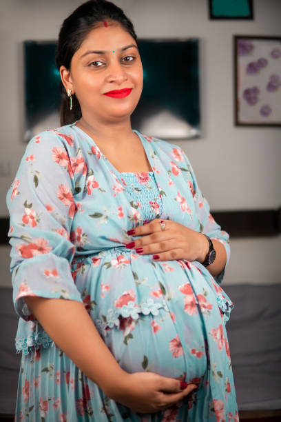 schöne lächelnde indische schwangere frau, die ihren bauch hält. - magen fotos stock-fotos und bilder