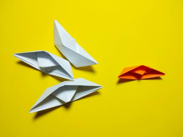 istock orange white paper boat falling Yellow background 1346029178