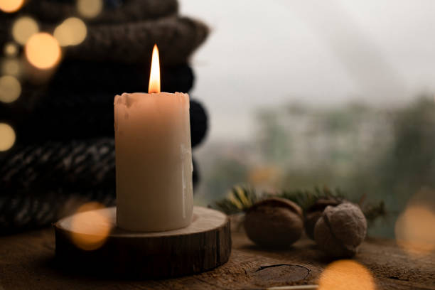 istock Burning candle on a wooden table near the window. Side view, place for text. 1346032291