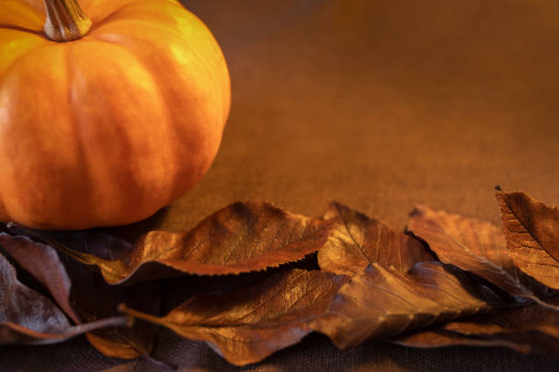 istock Autumn background with pumpkin and leaves on rustic wooden table. 1346032497