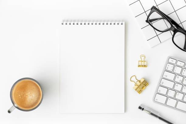 istock Blank notepad, cup of coffee, keyboard, glasses, binder clip, pen, notebook on white background. Business flat lay. Minimal online office mockup. Trendy hipster workspace. Top view, copy space 1346032589