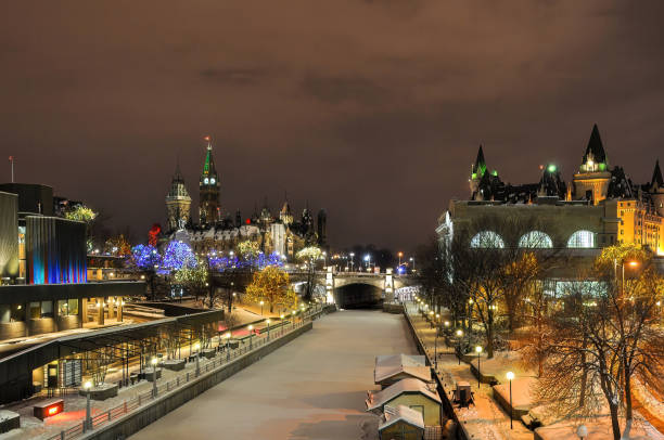 Winter night shot of Rideau Canal with Christmas lights in Ottawa, Canada Ottawa, Canada - December 16, 2009: Foggy winter night shot with Christmas lights of the National Arts Centre and Parliament Buildings, L, Rideau Canal, C, and Chateau Laurier, R. chateau laurier stock pictures, royalty-free photos & images