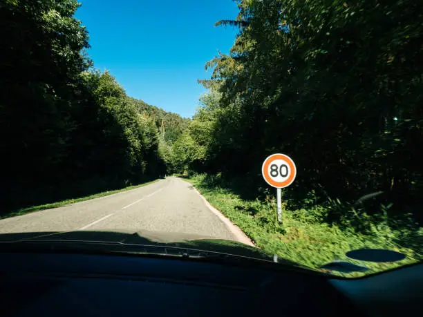 New French 80kmph speed limit sing seen on a public road in forest. As of July 1, 2018 the speed limit on two lane roads from 90 KMPH to 80 KMPH, in the hope addressing alarming rise in number of road deaths