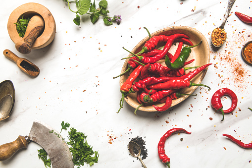 Close-up of jalapeño, yellow and red bell peppers, on rustic cutting board