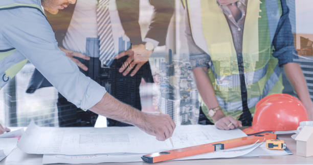 istock Double exposure of engineers team meeting for architectural project. architects discussing blueprint with construction manager in office worker conference site standing during overlay with construction site in the city. 1346033958