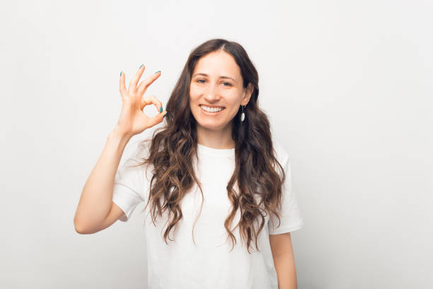 istock Stylish young woman is showing ok gesture while smiling at the camera. 1346034156
