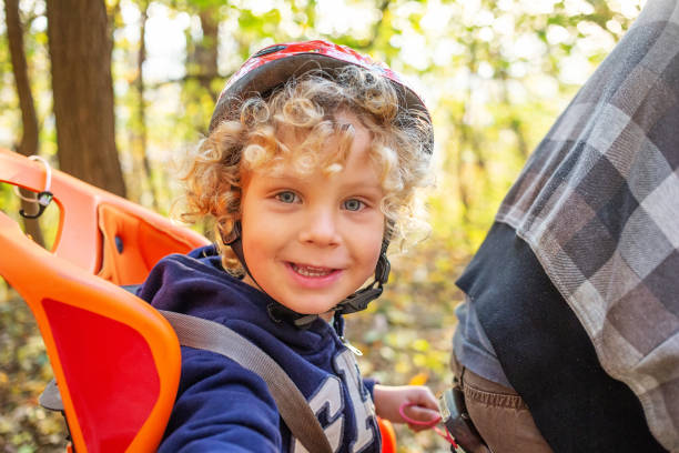 istock White curly boy in a helmet in a bicycle seat 1346035303