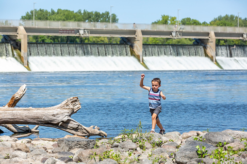 Young boy playing on the bank of the Mississippi River near the Coon Rapids, MN dam. Taken on a beautiful summer day.