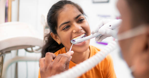 dentiste faisant le traitement des dents d’une patiente avec la caméra intra-orale à la clinique. - dentist teenager dental hygiene sitting photos et images de collection