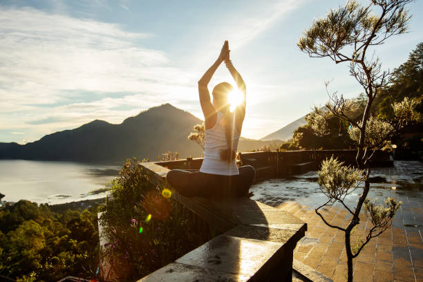 Donna che fa yoga all'alba vicino a un vulcano sull'isola di Bali - foto stock