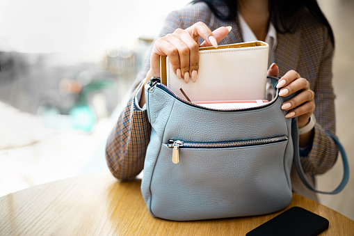 Top view business female hands pulling out pink notepad diary and pen ready to formal meeting or work. Elegant fashion white feminine handbag storage things and everyday life accessories organization