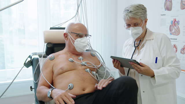 Doctor performing bicycle stress echocardiogram on senior patient