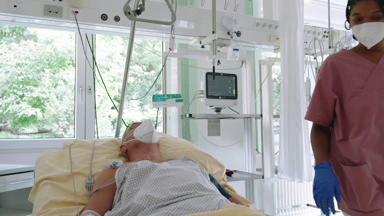 Nurse looking at the vital signs monitor of senior patient at intensive care unit