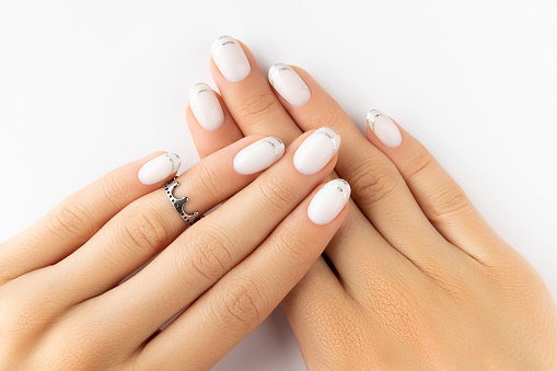 Beautiful groomed womans hands with modern french nail design on white background. Manicure pedicure beauty salon concept
