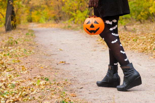 istock Women's legs in tights with bats walking through the Halloween forest 1346044106