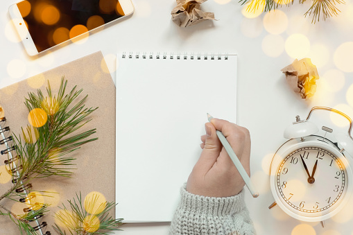 Back to life, goal list concept. Woman's hand writing in empty notebook. Resolutions, plan, goals, checklist, idea concept. Top view, flat lay, copy space. 2022. Christmas, New Year