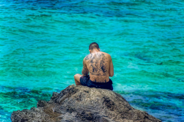 Ibiza, Spain, July 21 2018: A man is sitting and sun bathing on beach at Ibiza, Spain.