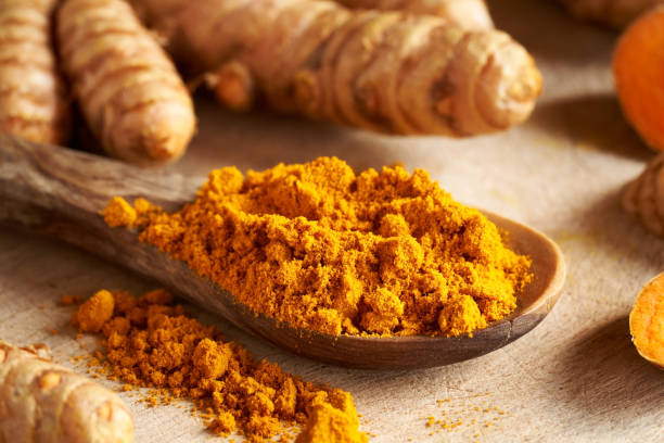 istock Turmeric powder on a wooden spoon with fresh root 1346050950