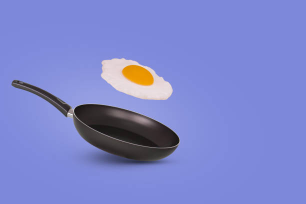 istock Creative idea with a frying pan and a flying fried egg on a purple background. Creative food concept. 1346051414