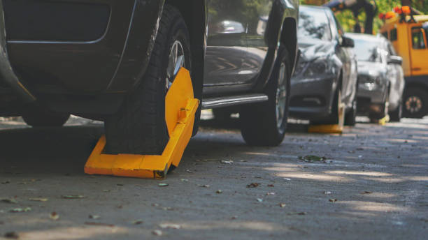 A parked car with a yellow tire lock for the illegal parking violation. Wheel lock-in restricted area for parking. Moody edited picture with shallow depth of field. car boot stock pictures, royalty-free photos & images