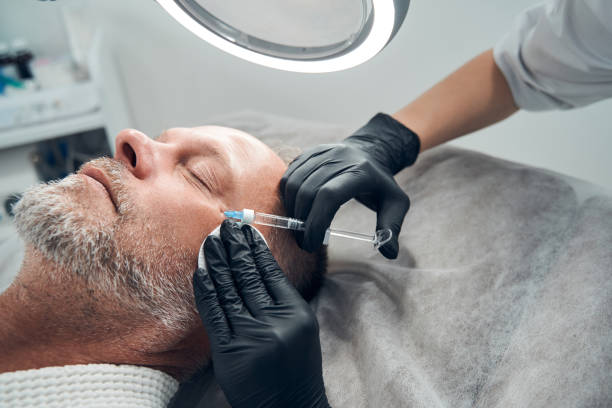 man receiving anti-aging injection in cosmetology salon - ogen dicht closeup vrouw 50 jaar stockfoto's en -beelden