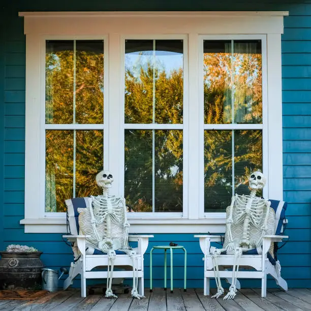 Photo of Skeletons sitting in chairs on porch for halloween