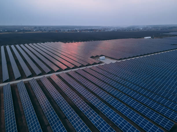istock Aerial drone view into large solar panels at a solar farm at bright sunset. Solar cell power plants. 1346060802