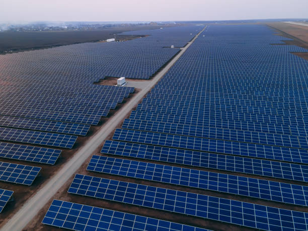 istock Aerial drone view into large solar panels at a solar farm at bright sunset. Solar cell power plants. 1346060805