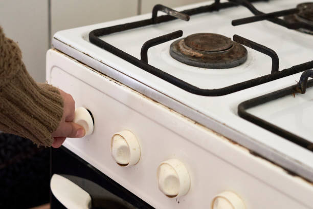 Woman checking gas, trying to turn on gas on old gas stove stock photo