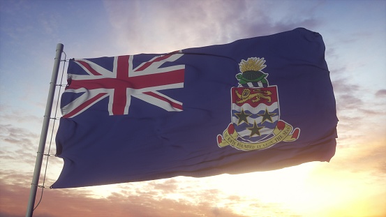Flag of Cayman Islands waving in the wind, sky and sun background. 3d rendering.